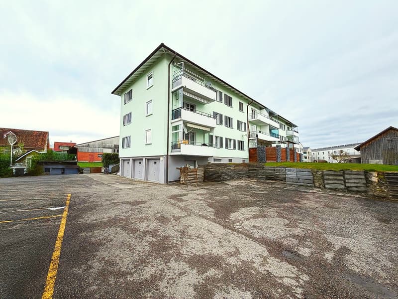 4 story building, green exterior, balconies, garage, parking lot