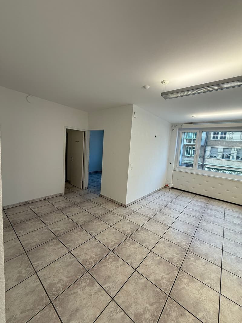empty room, white walls, tiled floor, two doors, windows, and ceiling lights