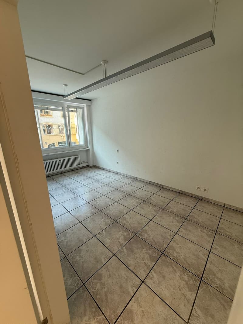 an empty room with large windows and a ceiling light