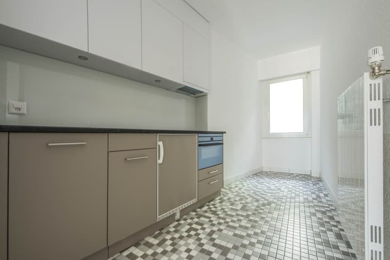 modern kitchen with white cabinets, tiled floor, built-in oven, dishwasher, power outlet
