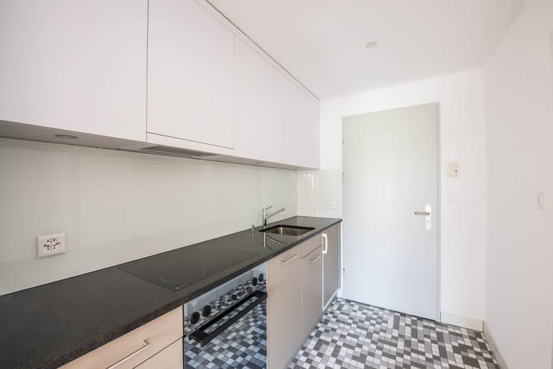 modern kitchen, white cabinets, black countertops, stainless steel sink, electric stove, dishwasher, power outlet