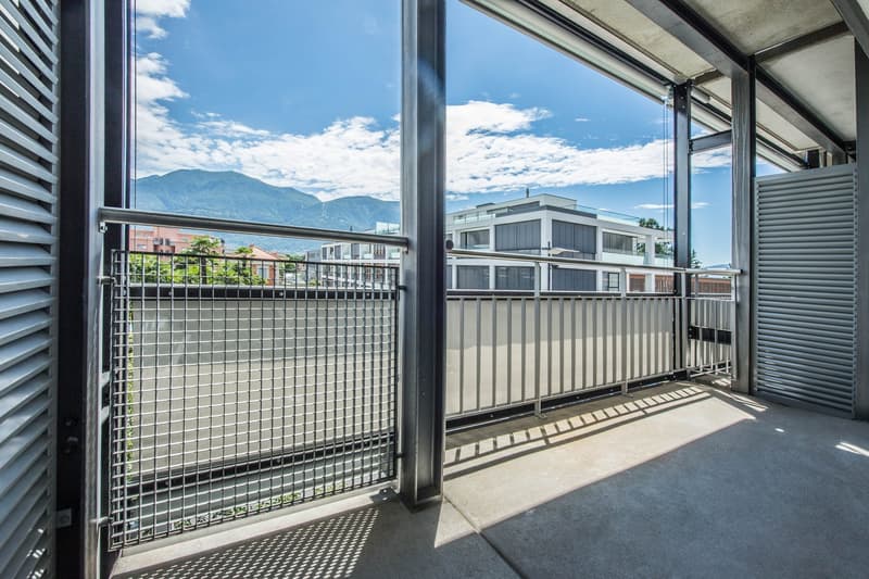 large balcony, metal railings, metal mesh fence, concrete floor, view of mountains