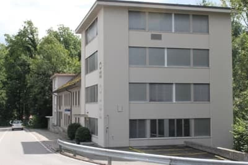 Office building, 4 floors, white exterior, large windows, parking lot in front