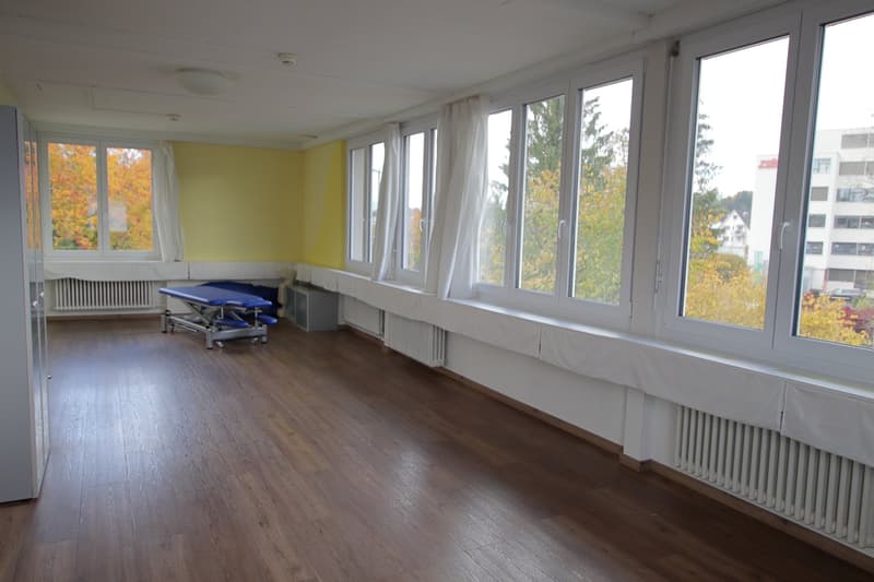 empty room, yellow walls, white windows, wooden floor, movable medical equipment, heating systems