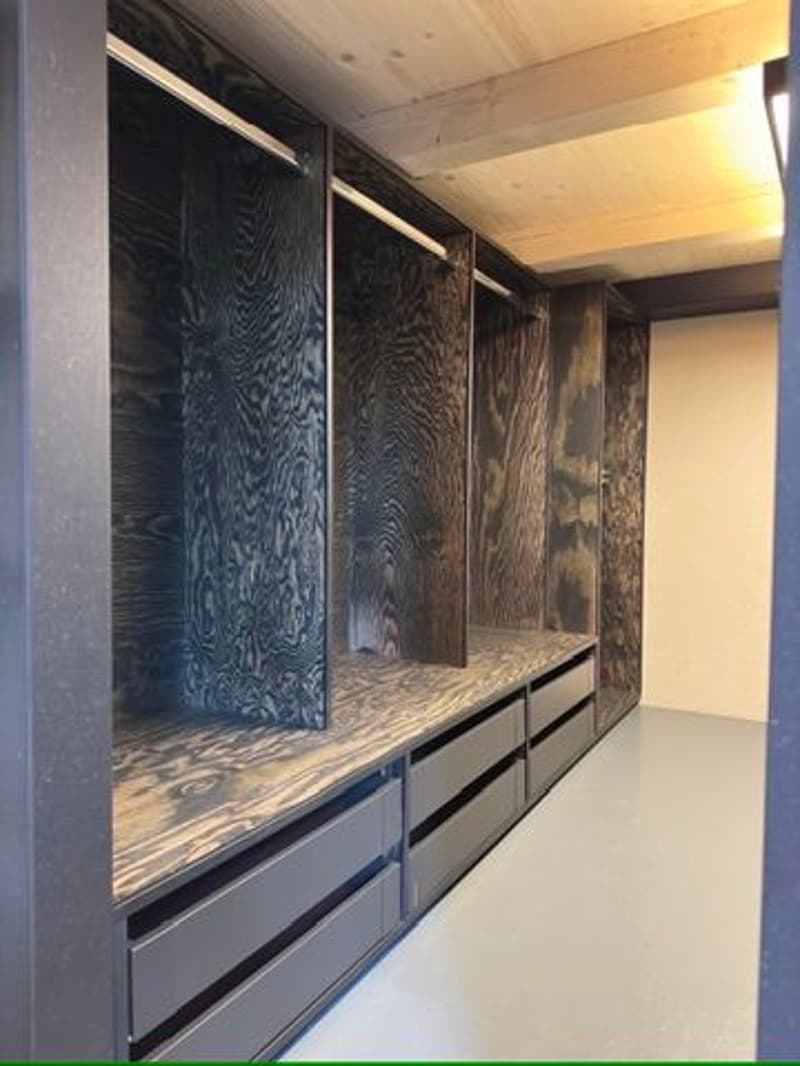 spacious closet, large dark wooden panels, open area, white floor, small lamp