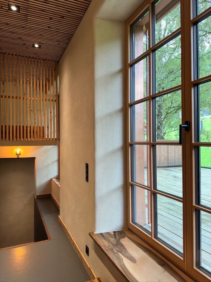 a wooden ladder, a window with a view of a wooden deck and a tree