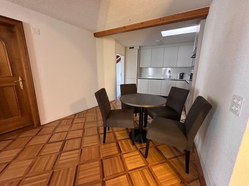 dining area with round table and chairs, wooden floor, kitchen visible