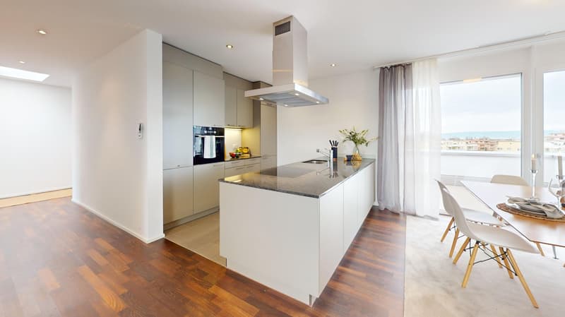 Modern kitchen with island, white cabinetry, granite countertops, stainless steel appliances, wooden flooring, and large windows.
