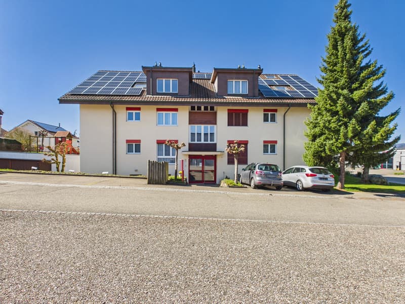 2 story house, white walls, red trim, solar panels on roof, 2 cars parked in front