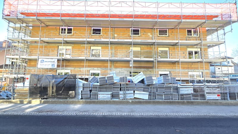 Building under construction, scaffolding, multiple windows, materials on the ground