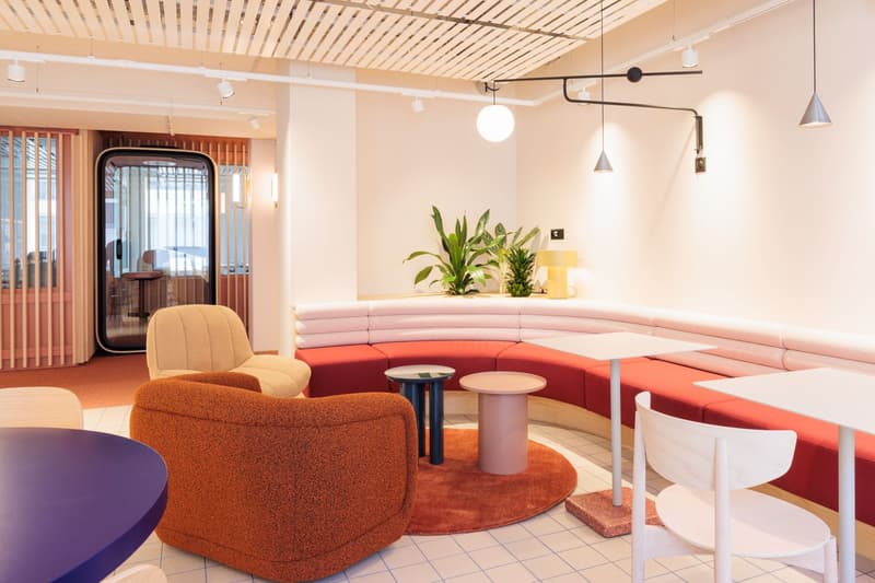 Open space with round tables, chairs, sofa, and plants on bench.
