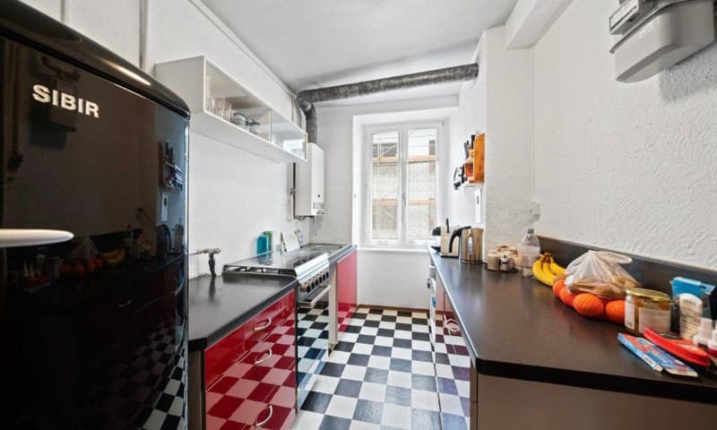 kitchen with black and white checkered floor, red cabinets, black fridge, black countertop, gas stove, oven, window