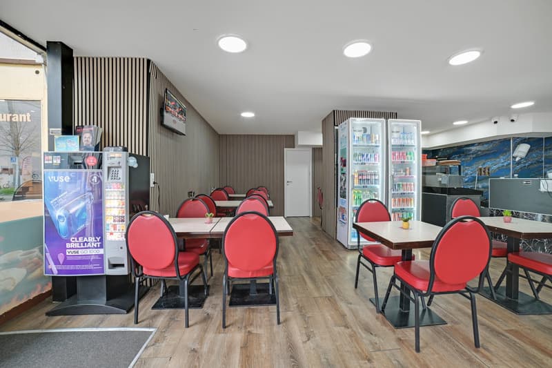 Dining area with tables and chairs, vending machines, refrigerators, and a wall-mounted TV