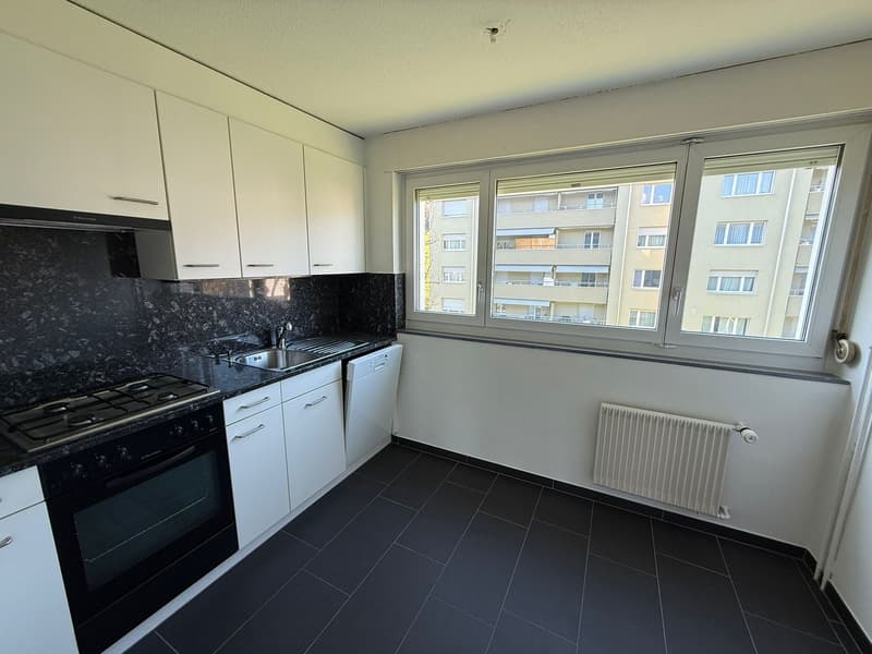 modern kitchen with white cabinets, black tiled floor, gas stove, dishwasher, sink, window
