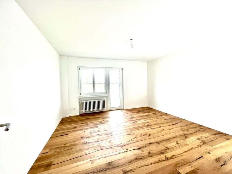 Empty room with white walls, hardwood floor, window, and a white radiator