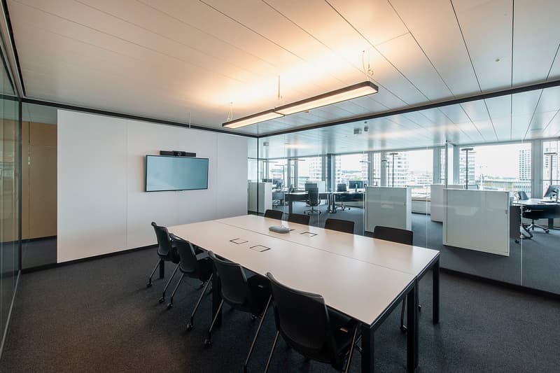 modern meeting room with glass walls, long table, chairs, large monitor on wall