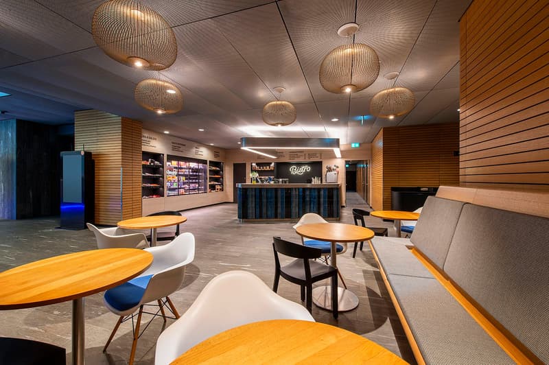 modern interior, wooden tables, white chairs, gray bench, wooden wall panels, hanging lamps, blue lighting, counter with Bistro sign