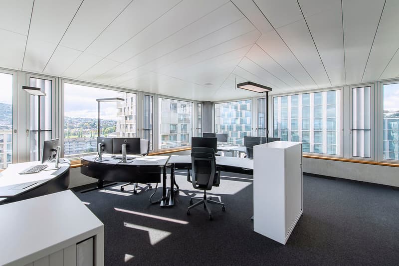 modern office with large windows, desks, chairs, monitors, lamps, carpeted floor