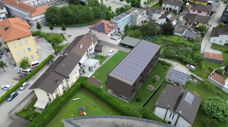 Neighborhood with multistory buildings, solar panels, greenery, and cars parked in the area