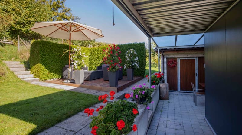 wooden deck, patio umbrella, flower pots, wooden steps, wooden door, brick wall, green lawn