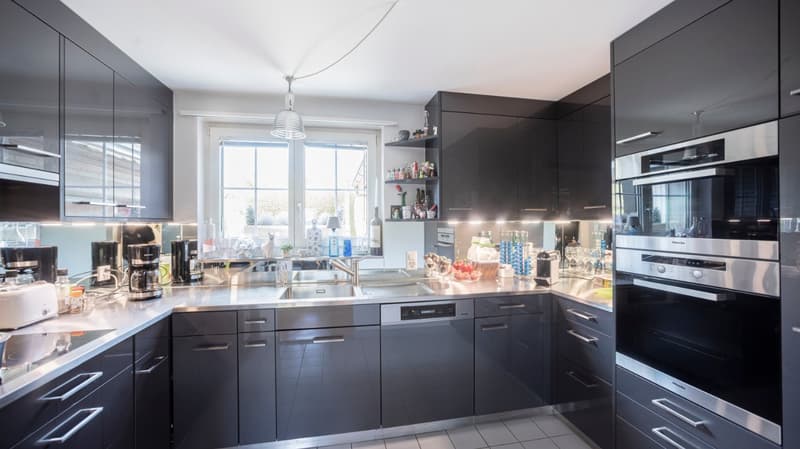 modern kitchen with stainless steel appliances, black cabinets, white tiled floor, large window