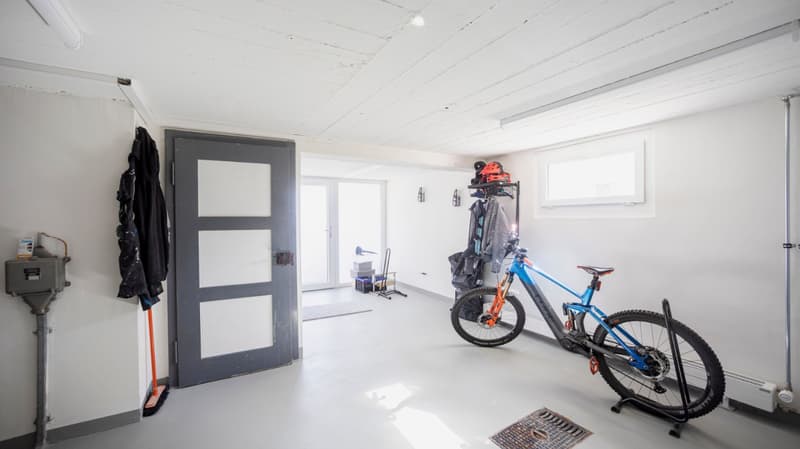 white walls, white ceiling, grey door, bicycle, storage rack, clothes hanging, white floor