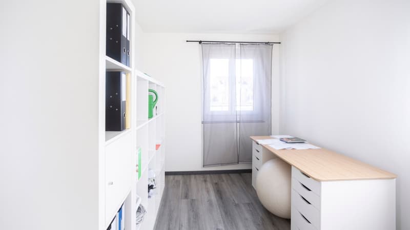 Desk, white shelves, white walls, wooden floor, window with curtains, exercise ball