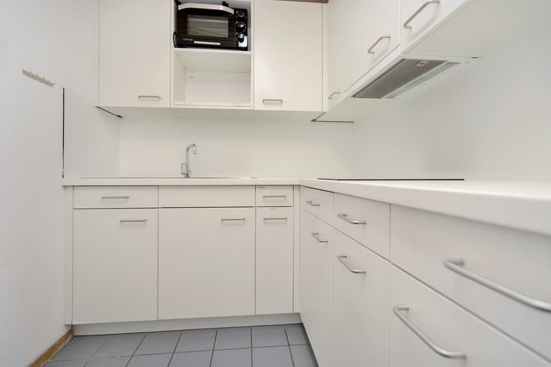 White cabinets, built-in oven, dishwasher, tile flooring