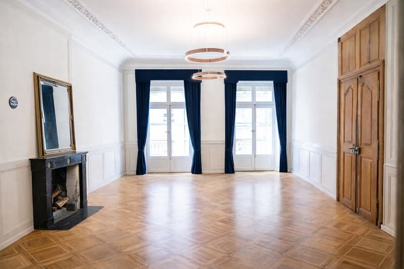 wide room, fireplace, hardwood floors, large windows, ceiling lamps