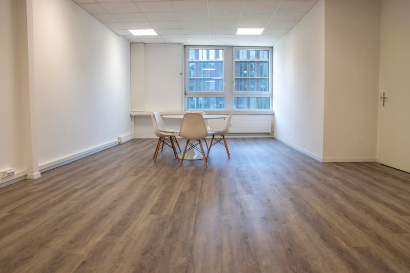 empty office room, hardwood floors, white walls, large windows, table and chairs