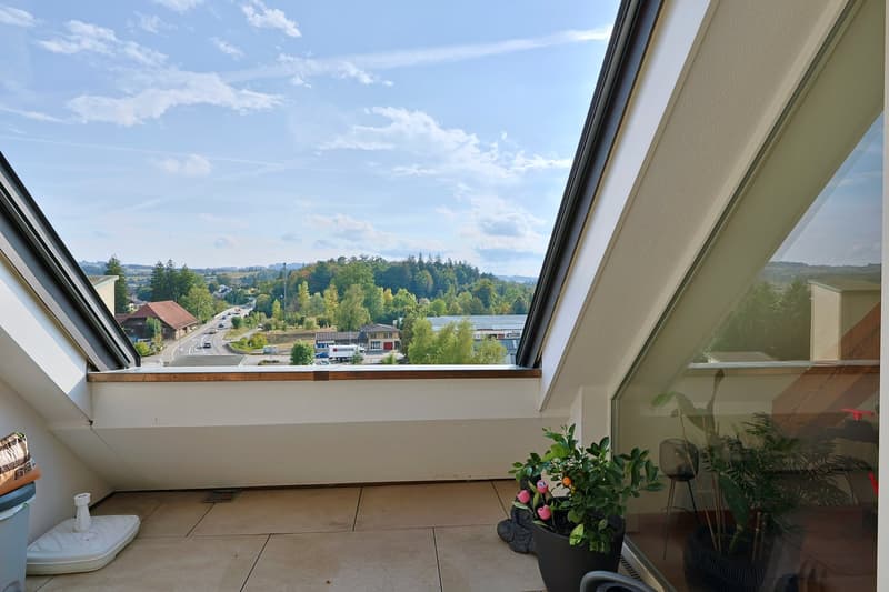 Ein teils überdachten Balkon mit Blick bis in die Berge.