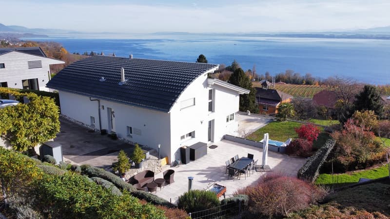 Modern white house, black roof, large windows, outdoor dining area, small pool, garden, sea view