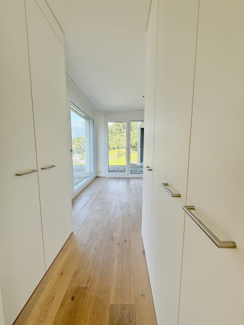 white walls, wooden floors, glass doors, windows with view of green landscape