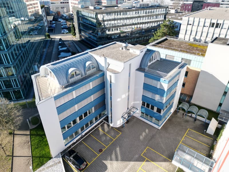 modern building, blue and white, multiple floors, windows, outdoor parking area, bicycles at entrance