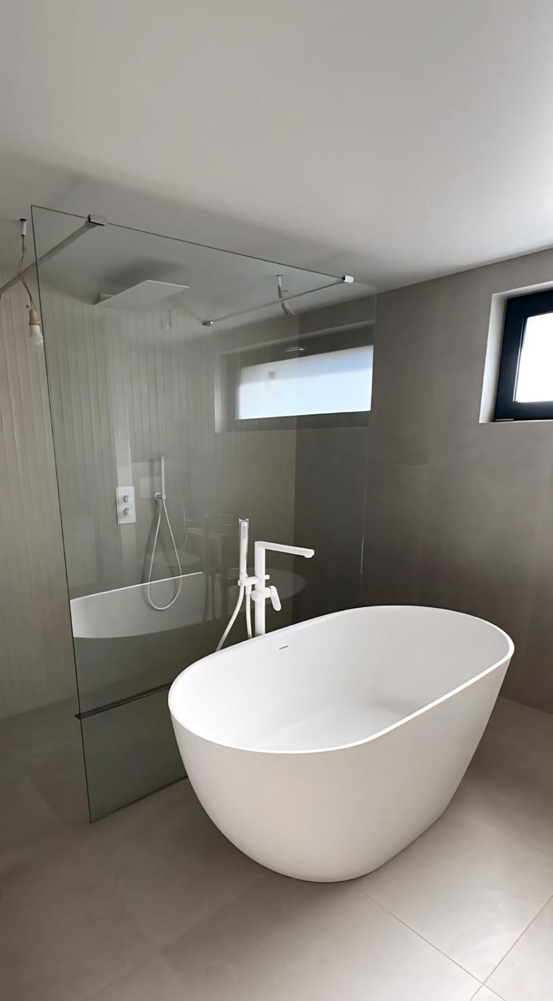 bathroom with glass enclosure, freestanding tub, and a separate shower area