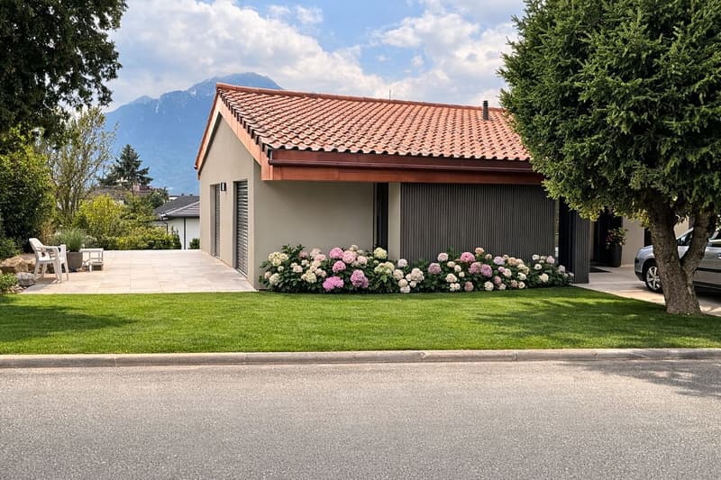 Modern single-family house, red roof, well-kept garden, car parked, shrubs, flowers