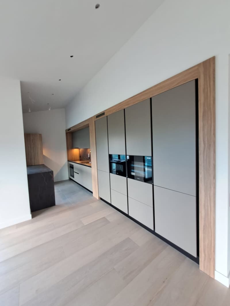 Modern kitchen, minimalist, white and gray cabinets, wooden trim, hardwood floor, central island with sink, microwave and oven