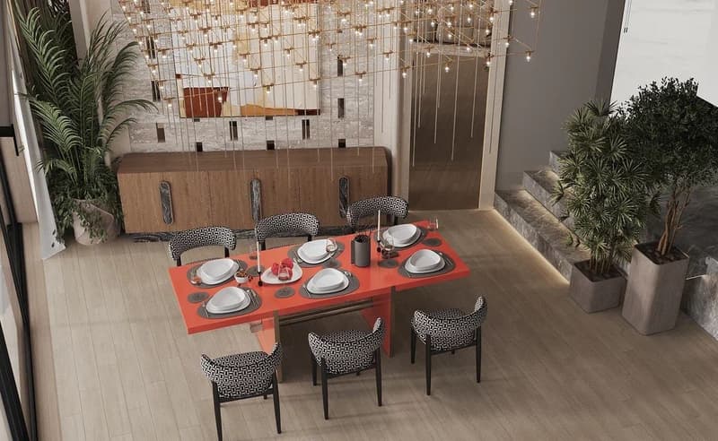 Dining room with a modern, stylish design. The room features a large wooden dining table with a bright orange top, surrounded by patterned upholstered chairs. The walls are decorated with a mirrored mosaic tile backsplash, creating a glamorous and reflect