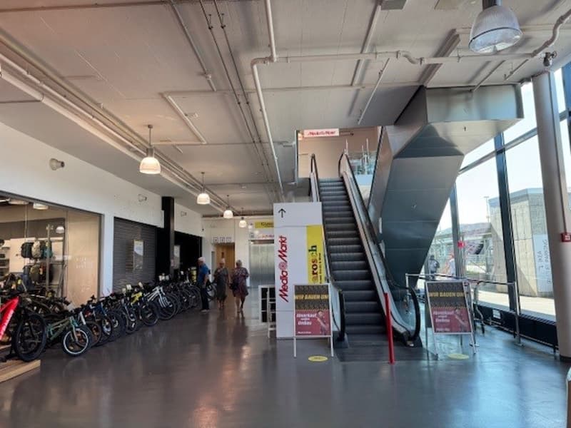 a shopping mall with rows of bicycles on display and a staircase and escalator