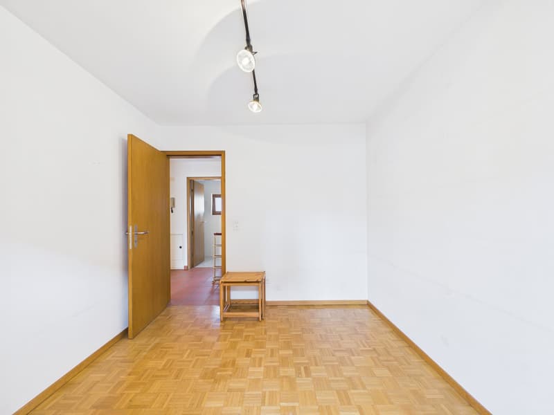 Empty room with white walls, wooden floor, door, small table