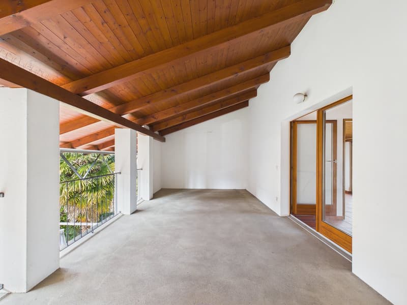large open room, wooden ceiling, grey floor, balcony, glass doors
