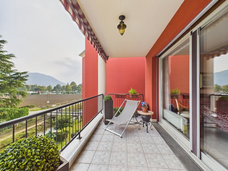 Balcony with a view of the mountains, a lounge chair, a small table, potted plants, and a lamp
