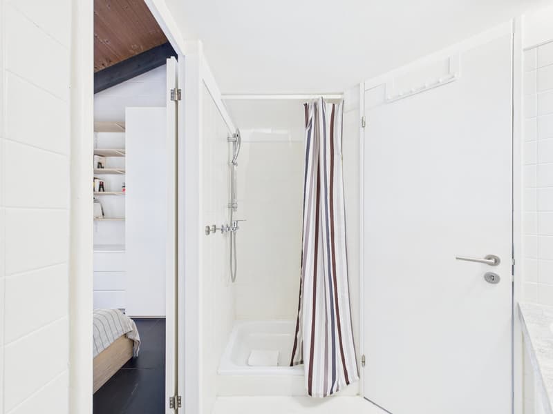 Bathroom with white tiles, shower, and wooden ceiling
