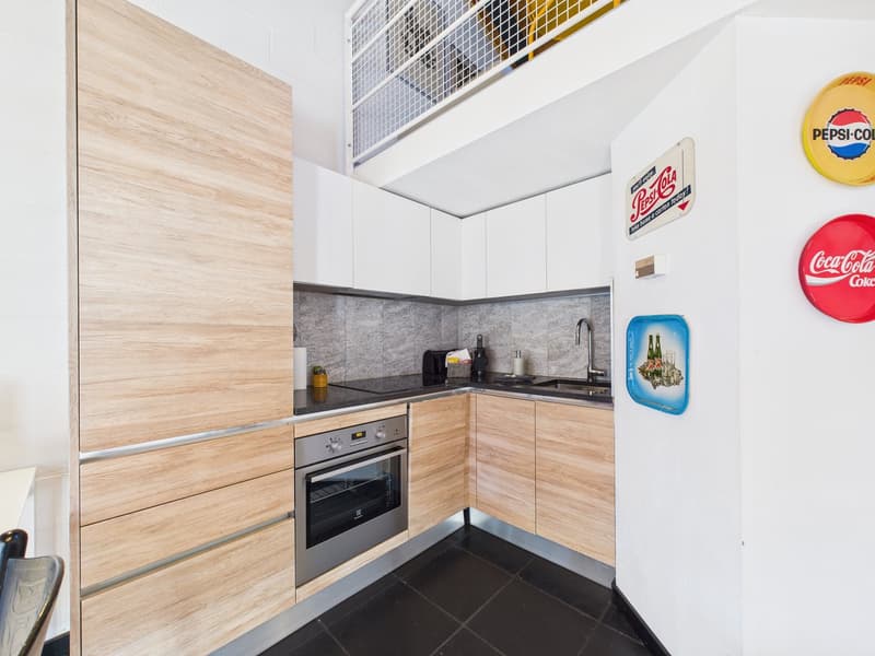 modern kitchen with wooden cabinets, black countertops, stainless steel appliances, tiled floor, decorative items on the wall