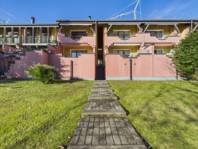 3 story apartment building, pink and yellow exterior, brick walkway, multiple balconies, green lawn