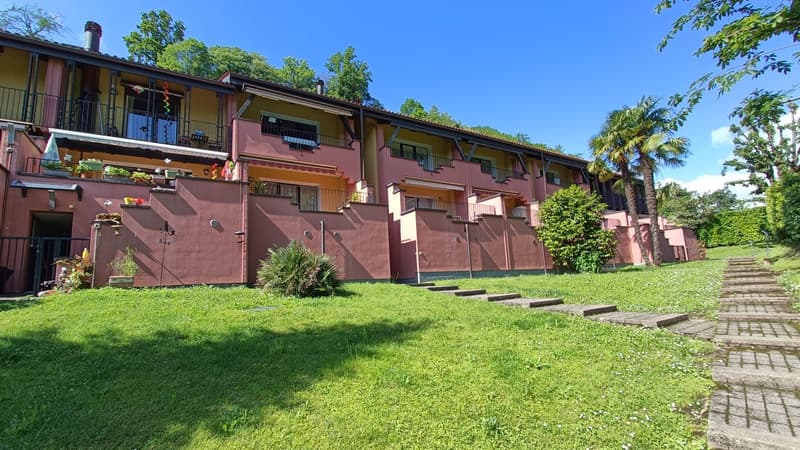 Apartment building, pink exterior, multiple balconies, green lawn, steps leading to entrance