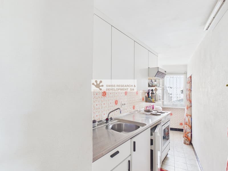 modern kitchen with white cabinets, stainless steel sink, gas stove, white oven, white tiled floor, white walls, window with view