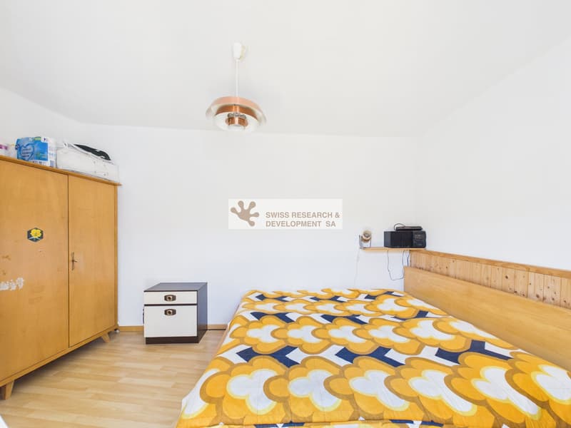 Bedroom with bed, wooden cabinet, nightstand, and ceiling lamp