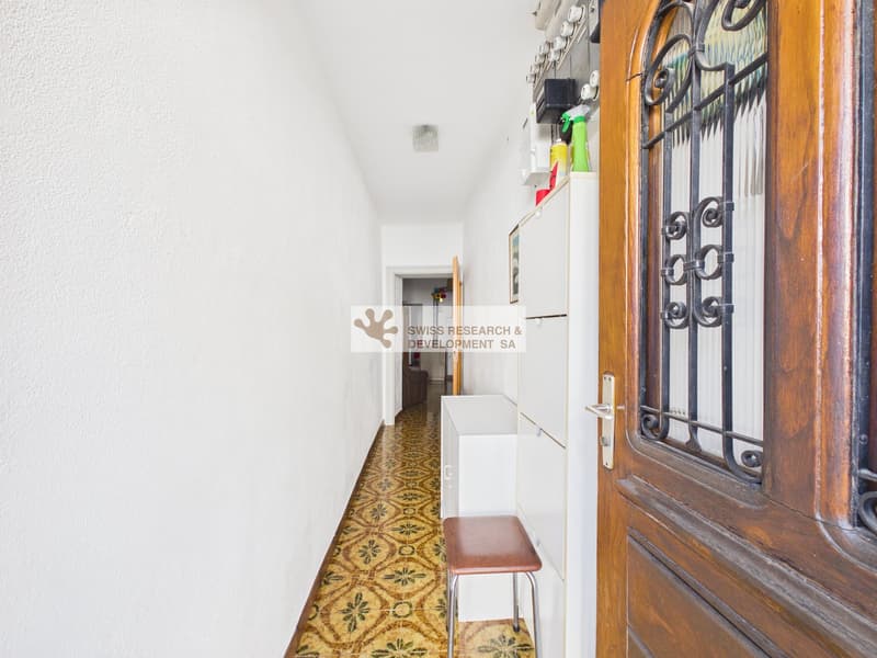 white walls, tiled floor, wooden door, small stool, white cabinets, cleaning products