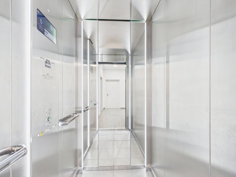 modern elevator with glass walls, silver interior, digital display, white tiled floor, stainless steel handrails